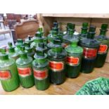 A COLLECTION OF TWENTY GREEN GLASS APOTHECARY BOTTLES WITH GILT BORDERED LABELS. (20)
