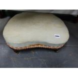 A VICTORIAN KIDNEY SHAPED FOOTSTOOL ON LEAF SCROLL SUPPORTS. W.45cms.