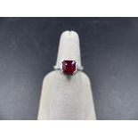 A WHITE METAL RUBY AN DIAMOND RING, STAMPED 750. THE CENTRAL RUBY IS SUSPENDED IN A DOUBLE FOUR CLAW