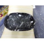 A CARVED STONE BOWL WITH MULTIPLE FOSSIL INCLUSIONS.