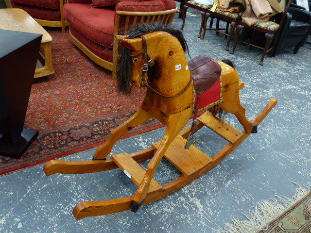 A LARGE CARVED PINE ROCKING HORSE.