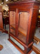 A GLAZED MAHOGANY BOOKCASE, THE TWO DOORS ENCLOSING SHELVES ABOVE A MIRRORED PANEL AND CYMA PLINTH