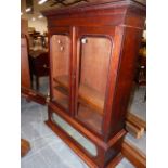 A GLAZED MAHOGANY BOOKCASE, THE TWO DOORS ENCLOSING SHELVES ABOVE A MIRRORED PANEL AND CYMA PLINTH