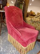 A LATE VICTORIAN WINE RED CORDUROY UPHOLSTERED LOW ARMCHAIR WITH TASSELLED APRON HANGING OVER THE