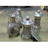 A PAIR OF ORIENTAL WHITE METAL PEPPER MILLS AND TWO ORIENTAL SILVER OVERLAID GLASS OIL BOTTLES. (4)
