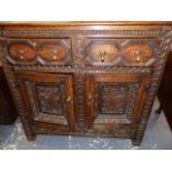 AN ANTIQUE AND LATER OAK DEUDDARN, THE CORNICE WITH PENDANT ENDS OVERHANGING TWO FOLIAGE CARVED