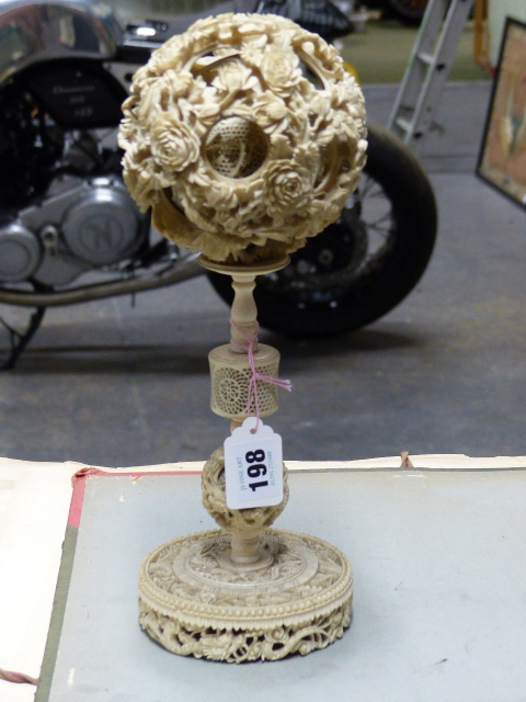 A CHINESE IVORY PUZZLE BALL CARVING WITH STAND HAVING A ROTATING RETICULATED KNOP AND A FURTHER
