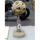 A CHINESE IVORY PUZZLE BALL CARVING WITH STAND HAVING A ROTATING RETICULATED KNOP AND A FURTHER