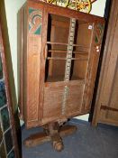 AN INTERESTING ART DECO LIMED AND DECORATED OAK CABINET WITH GLAZED DOOR ON COLUMN SUPPORT AND