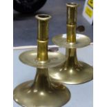 A PAIR OF 18th.C.BRASS CANDLESTICKS WITH IRON EJECTOR RODS IN THE CYLINDRICAL COLUMNS ABOVE THE WIDE