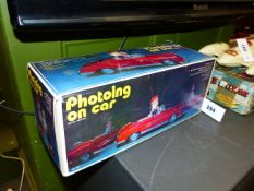 A CHINESE TINPLATE BATTERY OPERATED " PHOTOING ON CAR" TOY IN ORIGINAL BOX.