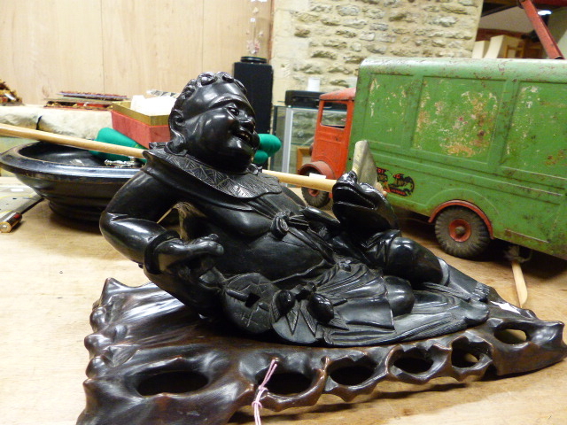 A CARVED HARDWOOD ORIENTAL FIGURE RECLINING WITH DRAGON.