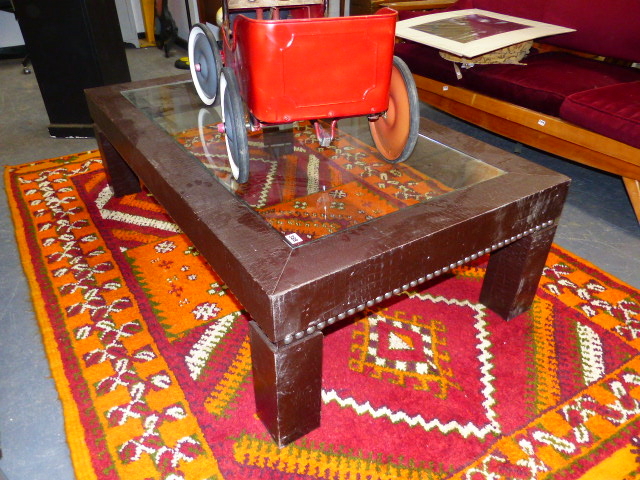 A CONTEMPORARY DESIGNER LOW TABLE WITH GLAZED TOP AND FAUX ALLIGATOR NAILED COVERING. W.1140 x H.