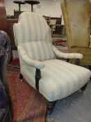 A VICTORIAN DEEP SEAT LOW ARMCHAIR ON TURNED FORELEGS WITH LATER PALE BLUE STRIPE UPHOLSTERY.