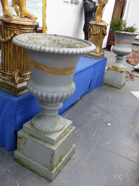 A PAIR OF ANTIQUE CAST IRON CAMPAGNA GARDEN URNS OF RIBBED FORM AND PLINTH BASES. OVERALL H.105cms.