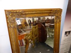 A BEVELLED GLASS RECTANGULAR MIRROR WITHIN A GILT FLUTED FRAME WITH FOLIAGE TREFOIL CORNERS. 154 x