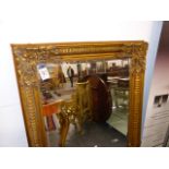 A BEVELLED GLASS RECTANGULAR MIRROR WITHIN A GILT FLUTED FRAME WITH FOLIAGE TREFOIL CORNERS. 154 x