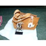 A RADLEY SMALL GRAB BAG IN LIGHT TAN LEATHER WITH TWO CHARMS AND DUST COVER.