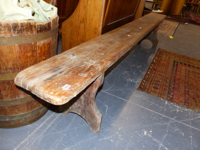 A PINE BENCH, THE RECTANGULAR TOP SUPPORTED AT EACH END BY BALUSTER PILLASTERS ROUND ARCHED AT THEIR