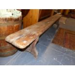 A PINE BENCH, THE RECTANGULAR TOP SUPPORTED AT EACH END BY BALUSTER PILLASTERS ROUND ARCHED AT THEIR