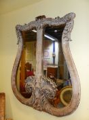 AN ANTIQUE CARVED LIMED OAK LYRE FORM FRAMED WALL MIRROR. W.130 x H.152cms.