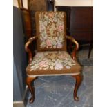 A QUEEN ANNE STYLE WALNUT ARMCHAIR WITH NEEDLEWORK BROWN GROUND FLORAL ENCLOSED CRESTED BACK AND