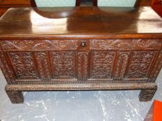 AN OAK COFFER, THE FOUR PANEL FRONT AND FEET CARVED WITH FOLIAGE, THE INTERIOR WITH A CANDLE BOX.