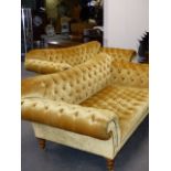 A PAIR OF BESPOKE QUALITY OCHRE BUTTONED VELVET SCROLL ARM SOFAS STANDING ON TURNED LEGS