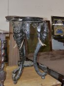 A VICTORIAN CARVED AND EBONISED STAND WITH ELEPHANT FORM SCROLLING SUPPORTS. H.72cms.