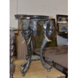 A VICTORIAN CARVED AND EBONISED STAND WITH ELEPHANT FORM SCROLLING SUPPORTS. H.72cms.