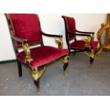 A PAIR OF EGYPTIAN STYLE EBONISED ARMCHAIRS, CRIMSON VELVET BACKS, THE GILT METAL ARM SUPPORTS