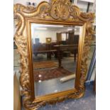 A GEORGIAN STYLE BEVELLED GLASS MIRROR, THE GILT FOLIATE FRAME CRESTED BY A SHELL. 130 x 90.5cms.