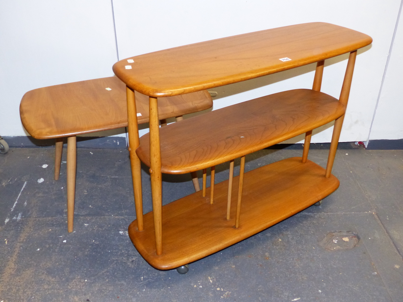 AN ERCOL ELM SET OF THREE FREE STANDING ROUNDED RECTANGULAR SHELVES ON CASTER FEET. W.91 x D.31 x