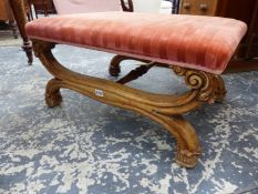 A VICTORIAN WALNUT STOOL, THE PEACH VELVET SEAT SUPPORTED ON THE LONG SIDES BY X-SHAPED LEGS FOLIATE