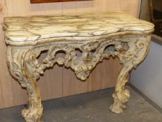 AN ITALIAN ROCOCO CARVED AND PAINTED MARBLE TOP CONSOLE TABLE OF SERPENTINE FORM WITH PIERCED