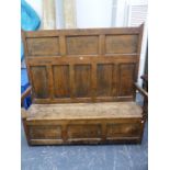 A 19th CENTURY PINE SETTLE, THE TALL SEVEN PANELLED BACK OVER A COFFER SEAT FLANKED BY ARMS. W.151 x