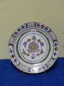 AN ENGLISH DELFT POLYCHROME DISH, THE CENTRAL RED ROSETTE BLOOMING WITHIN FOUR BUDS. Dia.34cms.