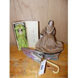 A PORCELAIN HEADED DOLL WEARING A BROWN DRESS. H 21cms. A BISQUE DOLL WEARING A GREEN CREPE PAPER