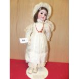 A SFBJ 60 BROWN HAIRED BISQUE HEADED DOLL WITH SLEEPING EYES AND WEARING LACE TRIMMED WHITE SILK.