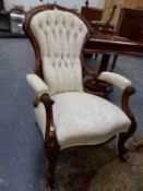 A VICTORIAN WALNUT SHOW FRAME ELBOW CHAIR BUTTON BACKED IN CREAM DAMASK, THE SCROLL FRONT LEGS ON