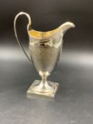 A GEORGIAN SILVER HALLMARKED HELMET SHAPED CREAM JUG WITH MONOGRAM ENGRAVING AND A GILDED INNER,