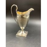 A GEORGIAN SILVER HALLMARKED HELMET SHAPED CREAM JUG WITH MONOGRAM ENGRAVING AND A GILDED INNER,