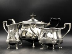 AN EDWARDIAN SILVER HALLMARKED THREE PART TEA SERVICE WITH A SHAPED GADROON RIM AND WOODEN HANDLE