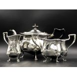 AN EDWARDIAN SILVER HALLMARKED THREE PART TEA SERVICE WITH A SHAPED GADROON RIM AND WOODEN HANDLE