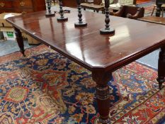 A LATE VICTORIAN MAHOGANY WIND OUT EXTENDING DINING TABLE WITH TWO LEAVES ON CARVED AND REEDED