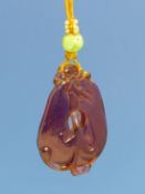 A CHINESE PEKING PURPLE GLASS PENDANT CARVED AS A DRAGON WITH ITS BODY THROUGH THE HOLE CENTRALLY TO