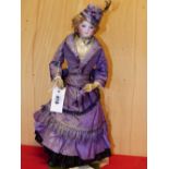 A FRENCH BISQUE HEADED DOLL WITH LEATHER COVERED BODY AND LIMBS, SHE WEARS A PURPLE SILK DRESS AND