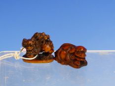 TWO CARVED WOOD NETSUKE DEPICTING BUDDHIST LIONS THAT RECLINE ON A FAN, SIGNED. W.4cms, THE OTHER