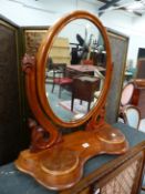 A VICTORIAN MAHOGANY OVAL DRESSING TABLE MIRROR, THE SCROLLED SUPPORTS ON A SHAPED PLINTH WITH TWO