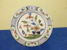 AN ENGLISH DELFT POLYCHROME DISH CENTRALLY PAINTED WITH A BUTTERFLY APPROACHING A FLOWER STEM. Dia.